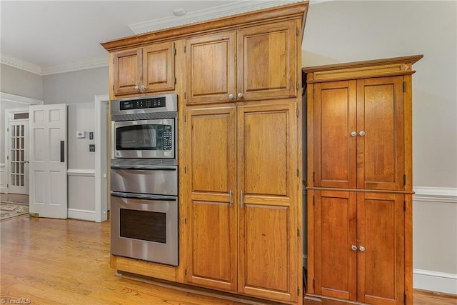5002 Leadenhall Rd, Oak Ridge, NC 27310 - kitchen with stainless steel oven, light wood-style floors, crown molding, and brown cabinetry