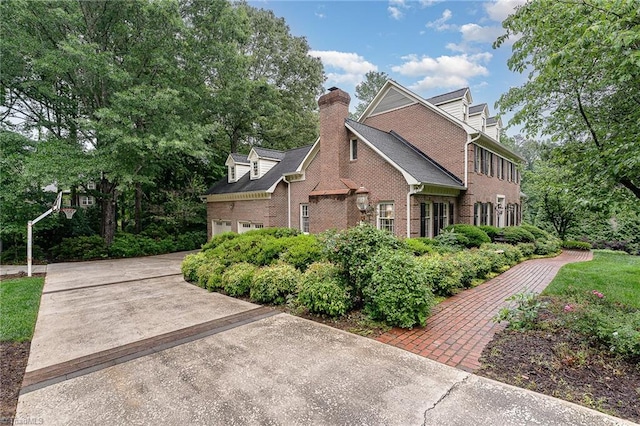 5002 Leadenhall Rd, Oak Ridge, NC 27310 - view of front facade with brick siding, a chimney, a garage, and concrete driveway
