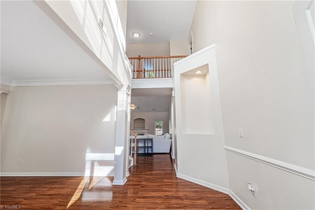 interior space with ceiling fan, decorative columns, hardwood / wood-style floors, a towering ceiling, and ornamental molding