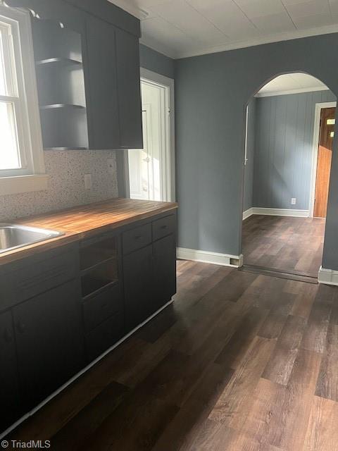 kitchen with dark wood-type flooring, crown molding, sink, decorative backsplash, and butcher block countertops