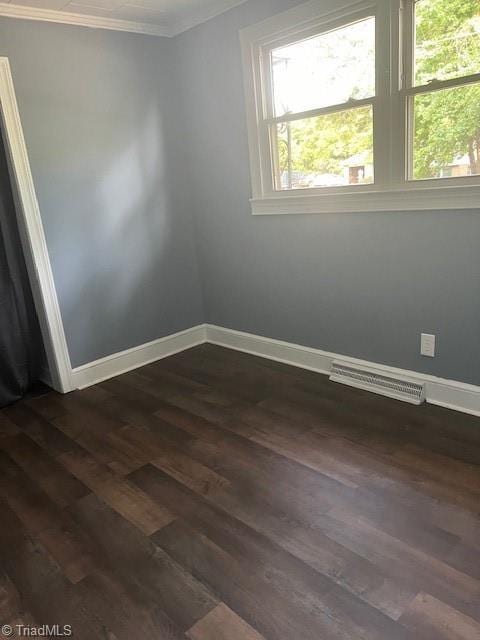 spare room with dark hardwood / wood-style flooring and ornamental molding