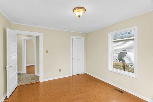 unfurnished room featuring light wood finished floors, visible vents, baseboards, and ornamental molding