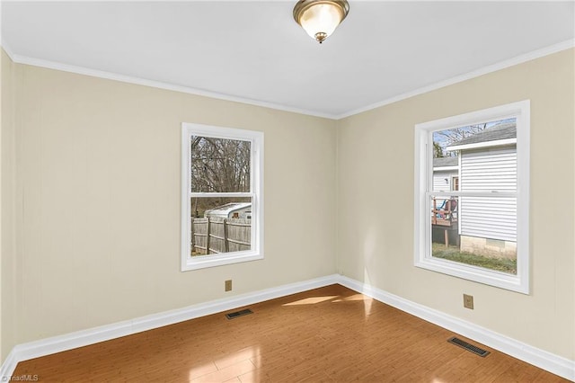 spare room featuring visible vents, baseboards, wood finished floors, and crown molding