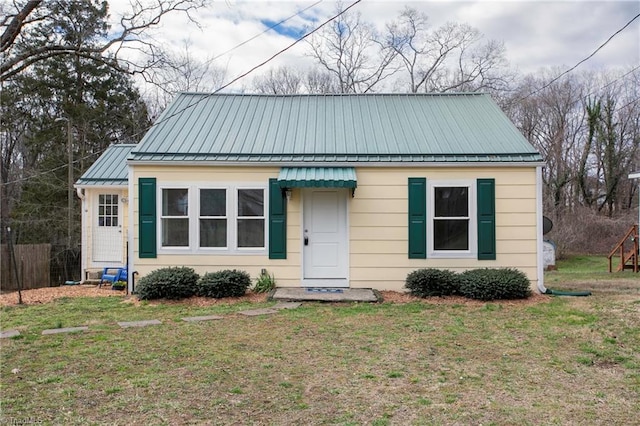 bungalow with a standing seam roof, metal roof, a front yard, and fence