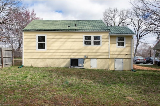 back of house featuring a lawn, a standing seam roof, central AC, fence, and metal roof