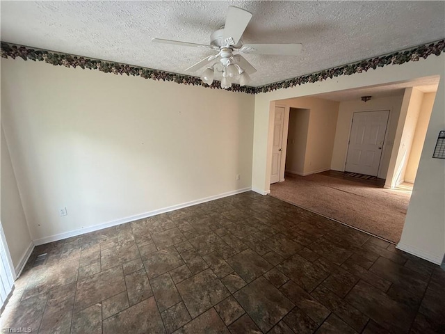 unfurnished room with baseboards, ceiling fan, stone finish floor, and a textured ceiling