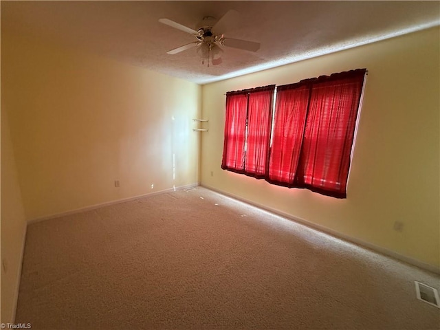 unfurnished room with carpet floors, ceiling fan, visible vents, and baseboards
