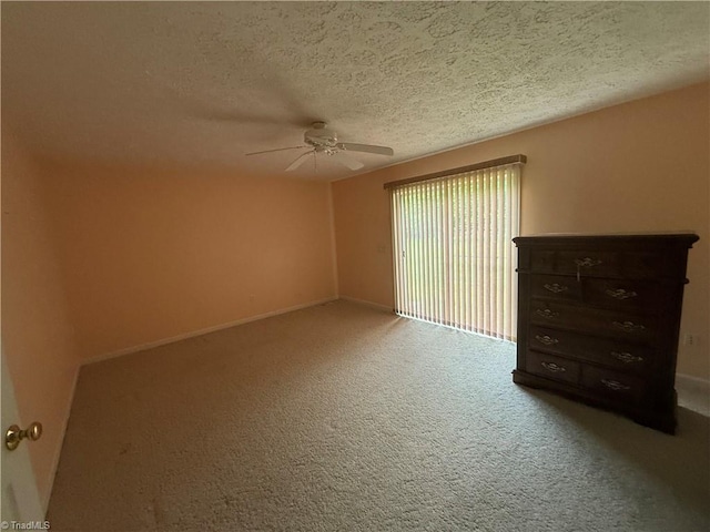 carpeted empty room with a ceiling fan, baseboards, and a textured ceiling
