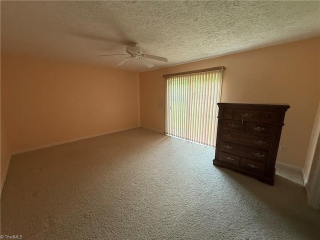 carpeted empty room with baseboards, a ceiling fan, and a textured ceiling