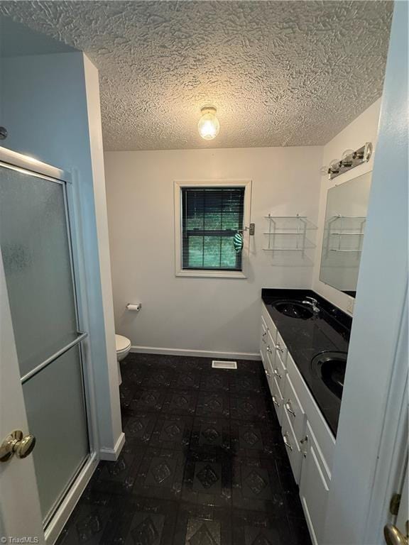 bathroom featuring toilet, a textured ceiling, a sink, and a stall shower