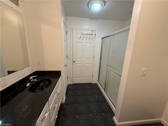 bathroom featuring vanity, a textured ceiling, baseboards, and a shower stall