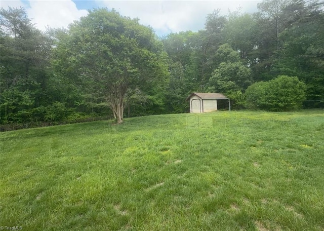 view of yard with an outdoor structure, a shed, a detached garage, and a forest view