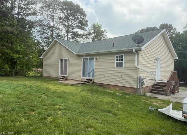 rear view of property featuring a yard, roof with shingles, fence, and entry steps