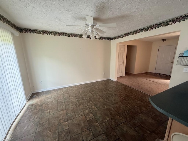 empty room with baseboards, a textured ceiling, ceiling fan, and stone finish floor
