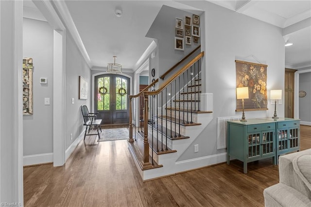 7823 Gatsby Pl, Greensboro, NC 27455 - foyer entrance with french doors, wood finished floors, stairs, crown molding, and a chandelier