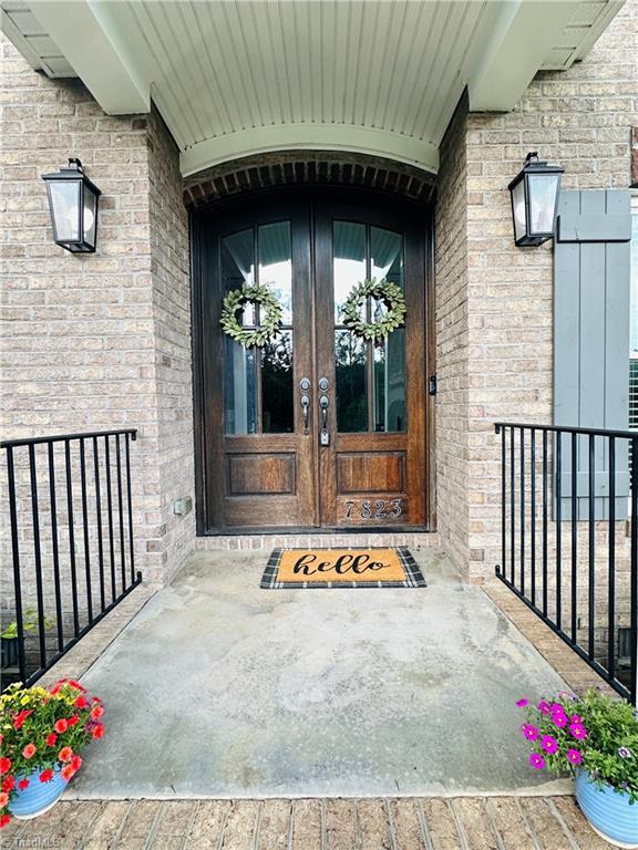 7823 Gatsby Pl, Greensboro, NC 27455 - property entrance with french doors, brick siding, and a porch
