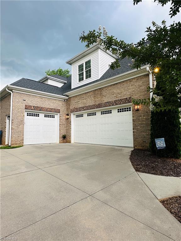 7823 Gatsby Pl, Greensboro, NC 27455 - traditional-style house featuring concrete driveway, brick siding, a shingled roof, and an attached garage