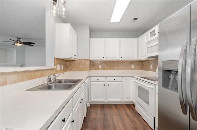 kitchen with dark wood finished floors, light countertops, white cabinets, a sink, and white appliances