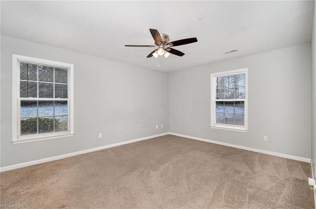 carpeted empty room with visible vents, ceiling fan, a textured ceiling, and baseboards