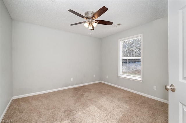 spare room with a textured ceiling, carpet floors, and baseboards