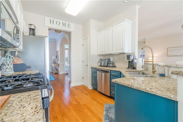 kitchen with blue cabinets, sink, light hardwood / wood-style flooring, appliances with stainless steel finishes, and white cabinetry