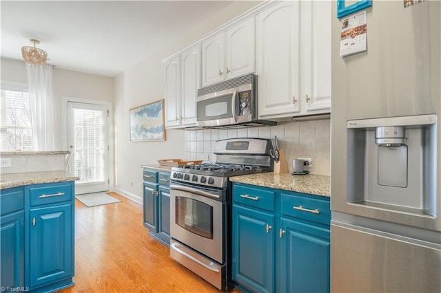 kitchen with white cabinets, appliances with stainless steel finishes, decorative backsplash, and blue cabinetry