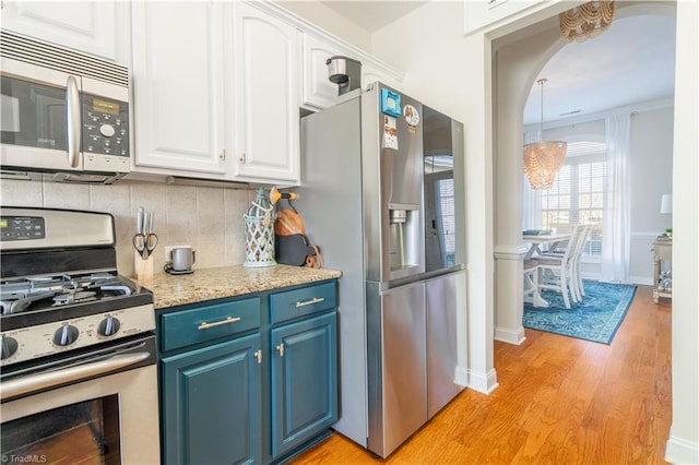 kitchen with light wood-type flooring, backsplash, stainless steel appliances, blue cabinets, and white cabinetry