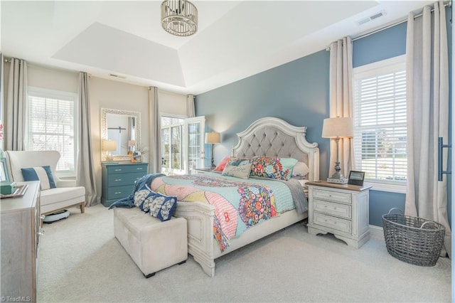 bedroom with a tray ceiling and light carpet