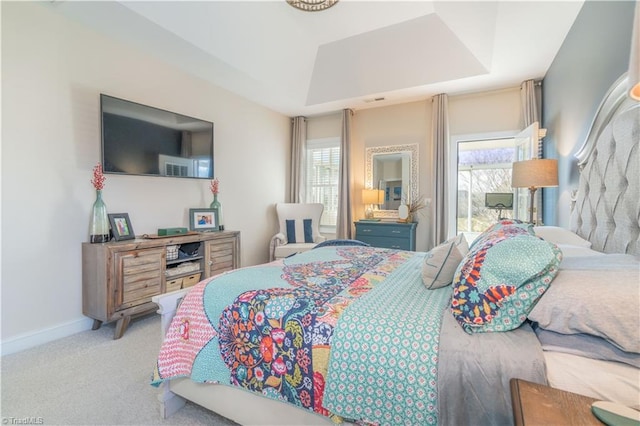 bedroom with a raised ceiling and light colored carpet