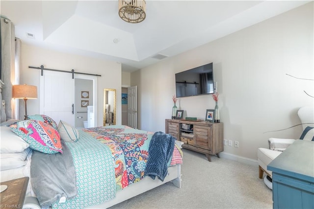 carpeted bedroom featuring a barn door and a raised ceiling