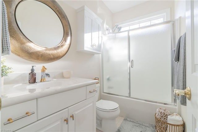 full bathroom with vanity, bath / shower combo with glass door, and toilet