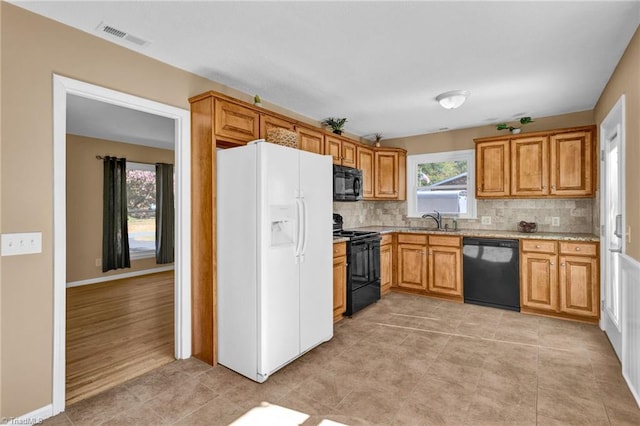 kitchen with tasteful backsplash, black appliances, sink, and light wood-type flooring