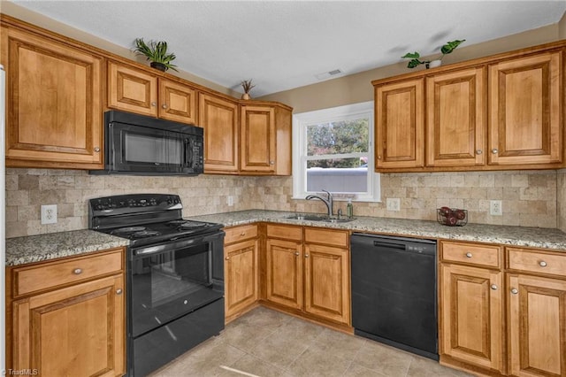 kitchen featuring sink, black appliances, light stone counters, and backsplash