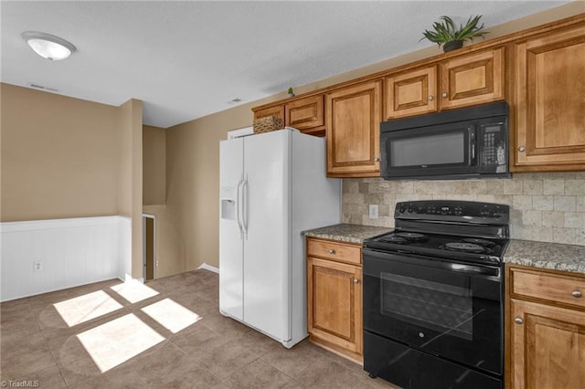 kitchen with black appliances, decorative backsplash, light stone counters, and light tile patterned floors