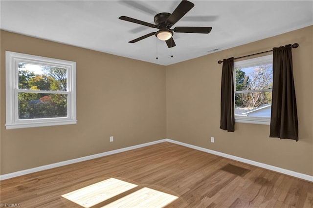 empty room with light hardwood / wood-style floors, a healthy amount of sunlight, and ceiling fan