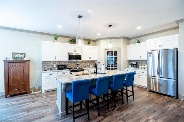 kitchen featuring a breakfast bar, an island with sink, dark wood-style flooring, white cabinets, and appliances with stainless steel finishes