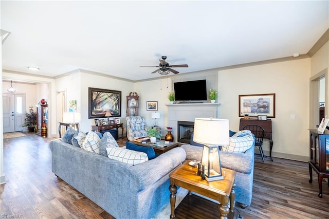 living area featuring ornamental molding, a fireplace, baseboards, and wood finished floors