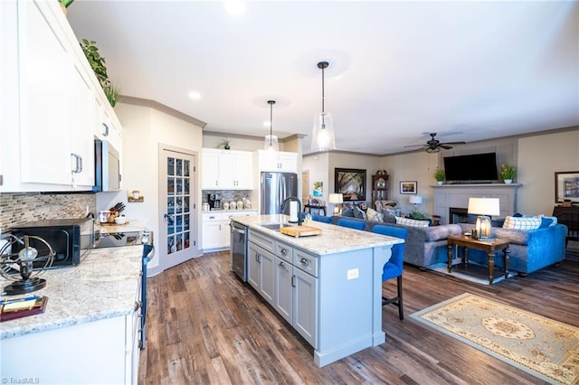 kitchen with dark wood-type flooring, a breakfast bar, a fireplace, white cabinets, and stainless steel appliances