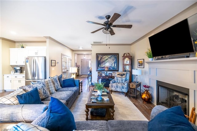 living room with visible vents, wood finished floors, a fireplace, and crown molding