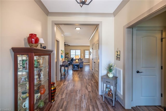 hallway with dark wood finished floors, crown molding, and french doors