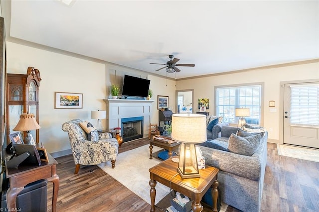 living area featuring ceiling fan, baseboards, wood finished floors, and a fireplace