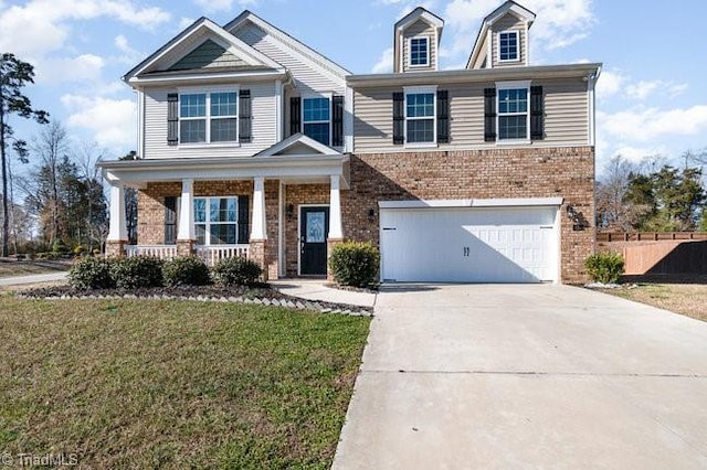 view of front of house featuring covered porch, a garage, and a front lawn