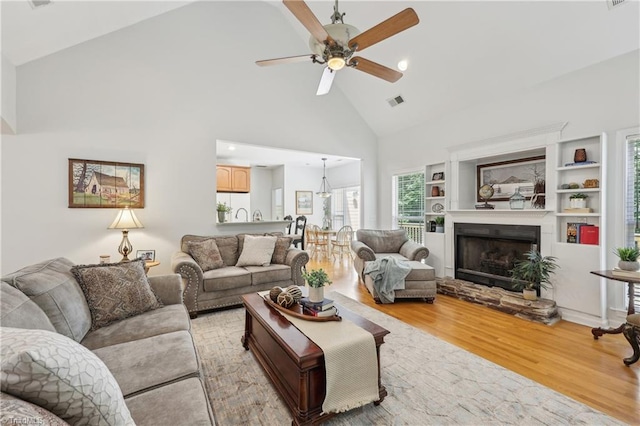 449 Wallburg High Point Rd, Winston-Salem, NC 27107 - living area featuring light wood-type flooring, high vaulted ceiling, ceiling fan, a fireplace with raised hearth, and built in shelves