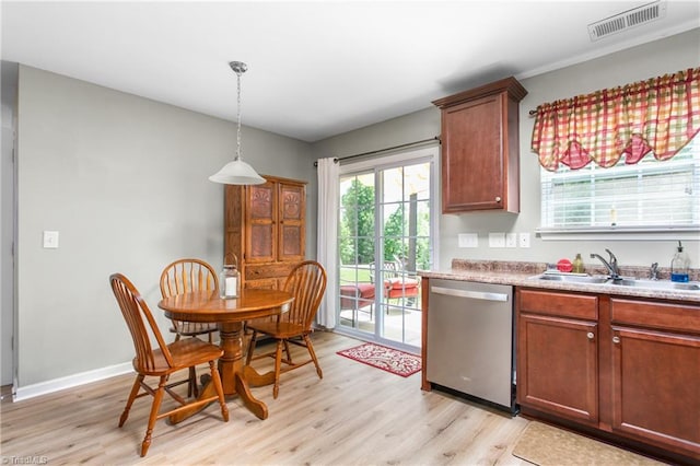 kitchen featuring plenty of natural light, stainless steel dishwasher, light wood-style flooring, and a sink