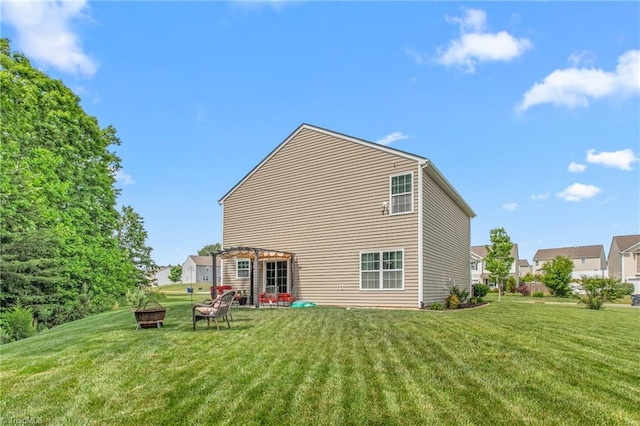 rear view of house featuring a fire pit and a lawn