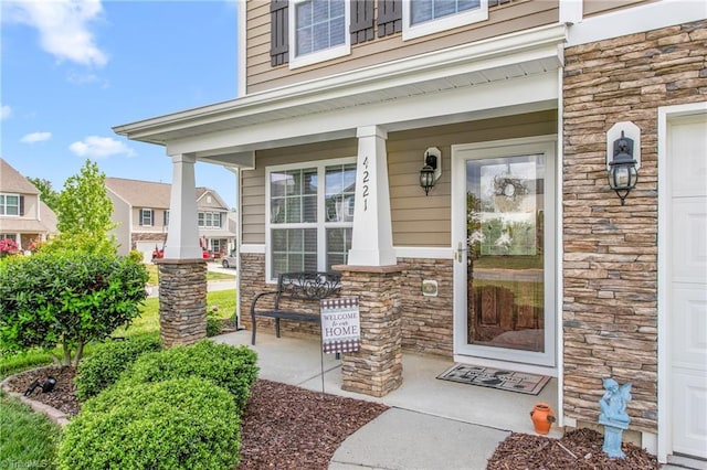 view of exterior entry featuring stone siding, covered porch, and a garage