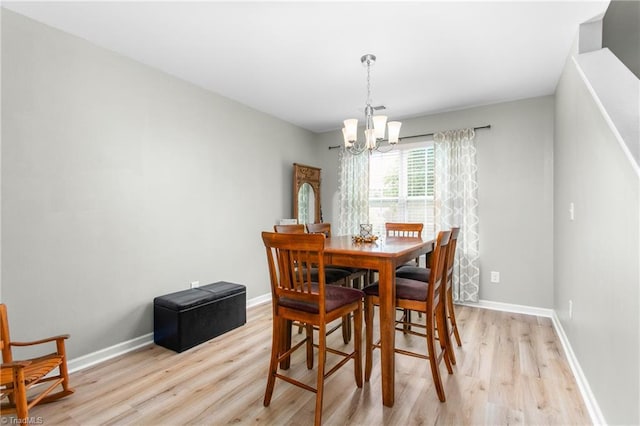 dining room with a chandelier, baseboards, and light wood-style floors