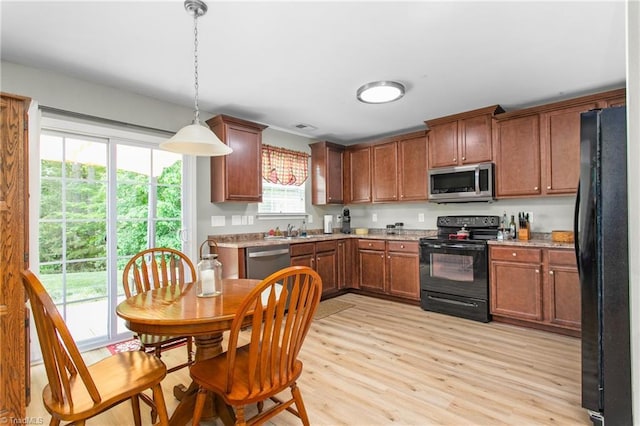 kitchen featuring black appliances, light countertops, light wood-style flooring, and a sink