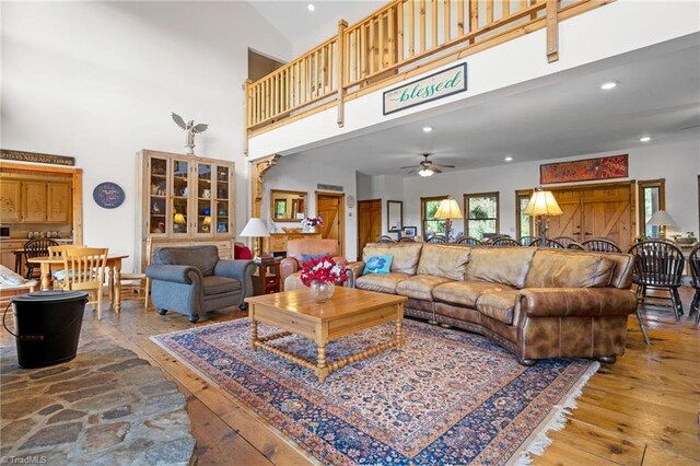 living room featuring ceiling fan, a high ceiling, and light hardwood / wood-style flooring