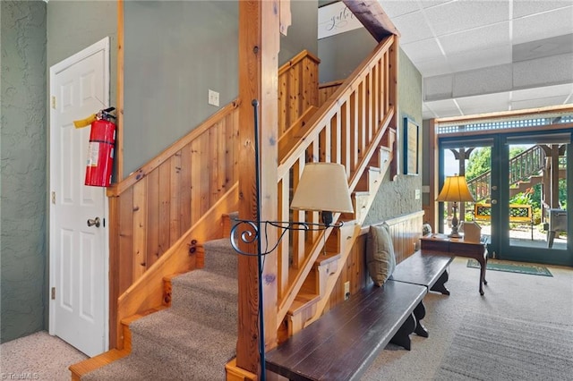 stairway featuring french doors, carpet floors, and a paneled ceiling